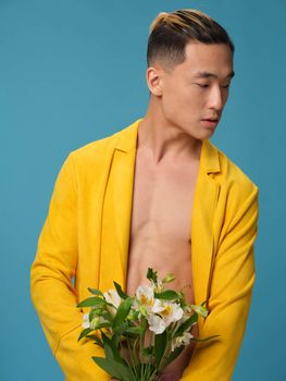 Handsome Asian male with bouquet of white flowers and coat pants front view. High quality photo