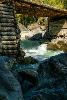 A wooden bridge made of logs across a mountain river.