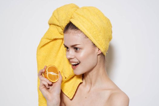 Cheerful woman with bare shoulders oranges holding a towel on her head with clean skin. High quality photo