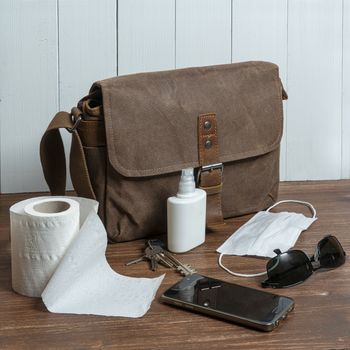 a bag and some objects and a roll of toilet paper on a wooden table