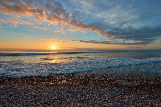 Several rocks on the beach in the warm light of a sunrise