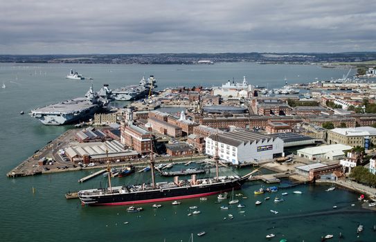 Aerial view of the Royal Navy dockyard in Portsmouth, Hampshire on a sunny summer day.  Aerial view including HMS Warrior, and the aircraft carriers HMS Queen Elizabeth and HMS Prince of Wales.
