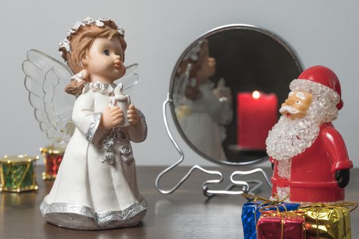 Christmas or new year's eve. Angel and Santa Claus with gifts at night on the background of a lit candle. New year holiday.