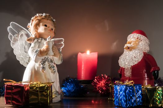 Christmas or new year's eve. Angel and Santa Claus with gifts at night on the background of a lit candle. New year holiday.