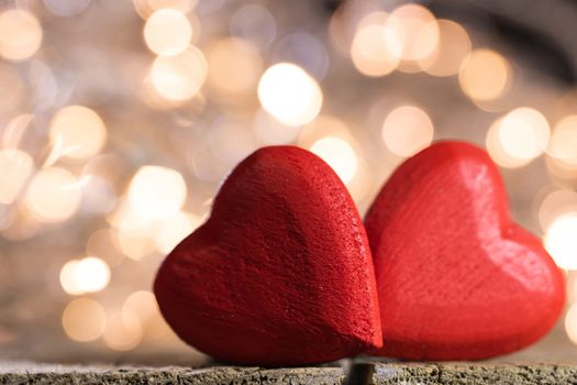 Two red wooden hearts symbol of love on background with beautiful bokeh party lights, Saint Valentine Day celebration