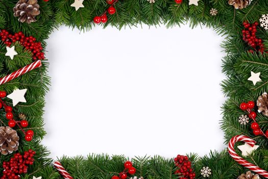 Christmas Border frame of tree branches around white background with copy space isolated, red decor, berries, stars, cones, candy canes
