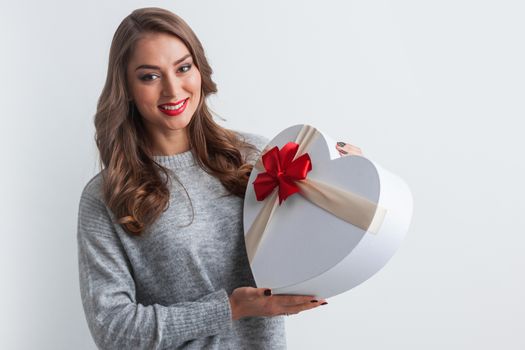 Beautiful happy girl with heart shape Valentine Gift box with red bow on white background