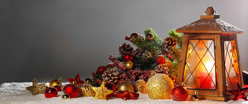 Christmas composition of lantern colorful ornaments balls stars candles and fir tree branches on snow