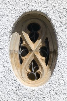 Ornate oval stone and lead glass church window with white wall, Mossel Bay, South Africa