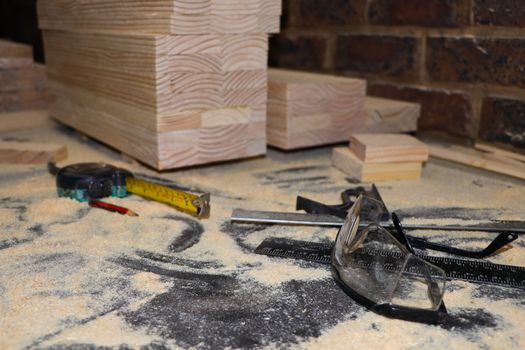 Safety glasses and measuring equipment on dusty bench with stacked wood, Pretoria, South Africa