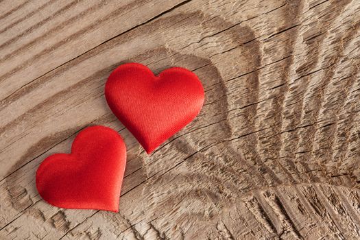 Valentine's day two red silk hearts on wooden background, love concept