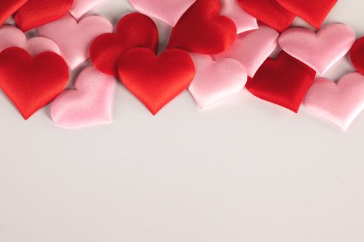 Valentine's day many red and pink silk hearts on white background , border frame with copy space, love concept