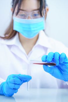 Technician scientist analyzing a blood sample in test tube in laboratory for testing it on COVID, COVID-19, coronavirus virus analysis