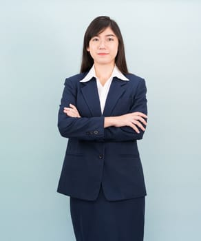 Teenage girl long hair is standing with her arms crossed wearing suit and white shirt on blue background