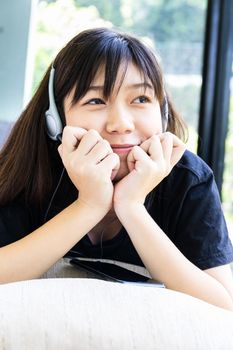 Teenage girl with headphones and listening to music from mobile phone at home