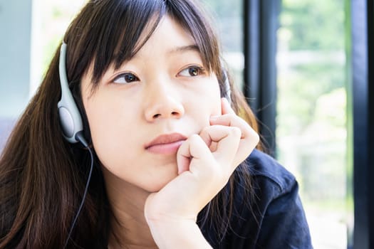 Teenage girl with headphones and listening to music from mobile phone at home