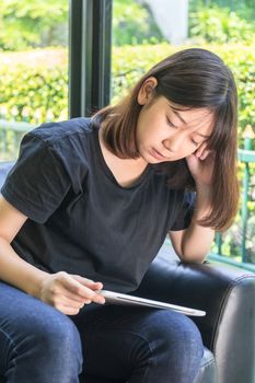 Young girl studying online from digital tablet on the sofa in parlor at home