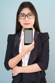 Young women in suit holding her smartphone standing against blue background