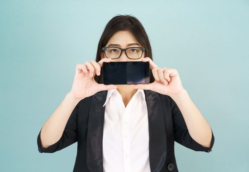 Young women in suit holding her smartphone standing against blue background