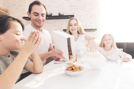 Children and parents eat breakfast. Family eating cereals with milk