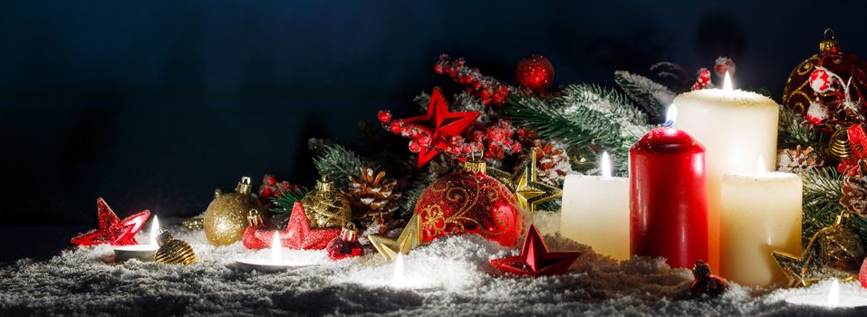 Christmas composition of colorful ornaments balls stars candles and fir tree branches on snow