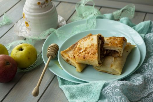 Apple cinnamon crepes. Pancakes with caramelized apples and cinnamon. Teal background