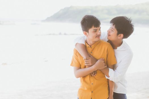 Homosexual portrait young asian couple standing hug together on beach in summer, asia gay going tourism for leisure and relax with romantic and happiness in vacation at sea, LGBT concept.