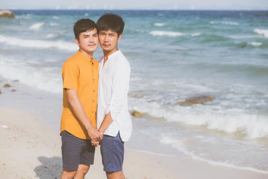 Homosexual portrait young asian couple standing together on beach in summer, asia gay holding hands going sea for leisure and relax with romantic and happy in vacation at sea, LGBT with legal concept.