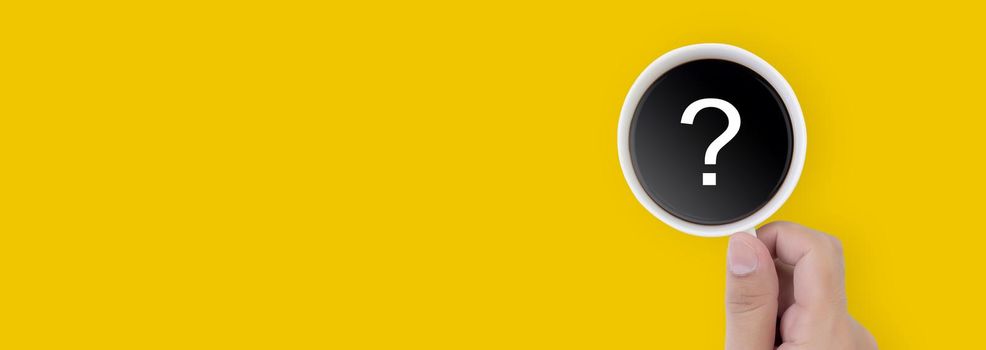 Hand holding cup of hot coffee with question mark isolated on yellow background, top view, q & a, faq or assistance for incentive, beverage or breakfast, communication and idea concept, banner website