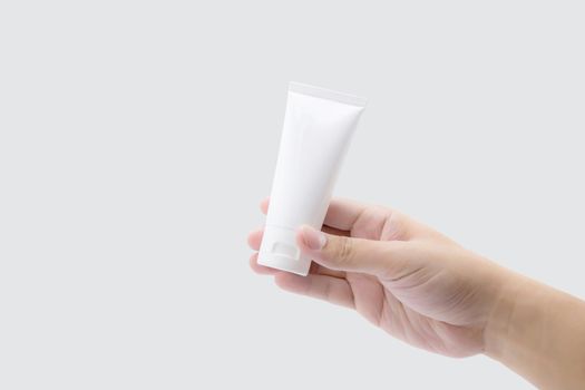 Hand of man holding mockup product about cream or lotion in tube isolated on white background, face foam, alcohol gel, skin care, package of treatment and moisturizing, design and presentation.