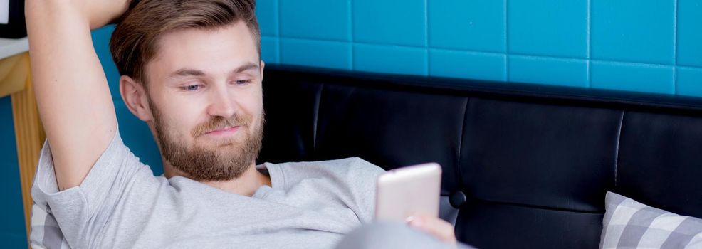 Young man using smartphone for relax on sofa at home, texting message or chatting on phone in internet online on couch for resting, device and technology, communication and lifestyle concept.