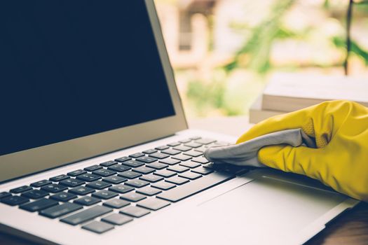 Hand of man cleaning keyboard computer with antibacterial for protect epidemic disease covid-19, fabric having antiseptic alcohol clean and wash laptop for on desk, business and health concept.