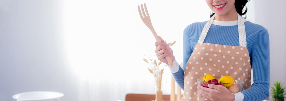 Happy young asian woman wearing apron preparing to cook in kitchen at home, chef with culinary, restaurant and proud, domestic life, portrait girl cheerful and happy cooking food, lifestyle concept.