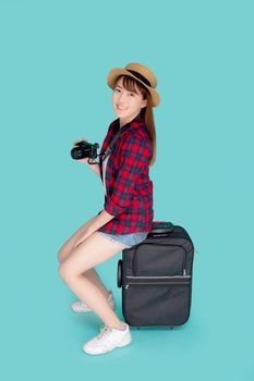 Beautiful portrait young asian woman sitting on luggage smiling and travel summer trip for abroad in vacation, happy asia girl holding camera sitting on suitcase for journey with cheerful in holiday.