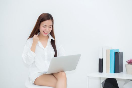 Beautiful of portrait happy young asian woman using laptop work with success on chair in the home, girl and notebook shopping online with glad, communication concept.