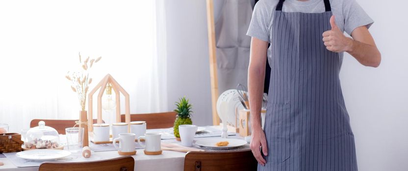 portrait of a smiling male cook gesturing visit sign in the kitchen