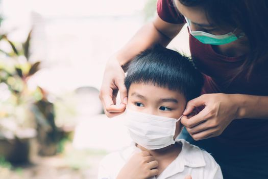 Mother take care son with face mask for protection disease flu or covid-19 outdoors, mom wearing on medical mask with child safety for protect outbreak of pandemic in public, medical concept.