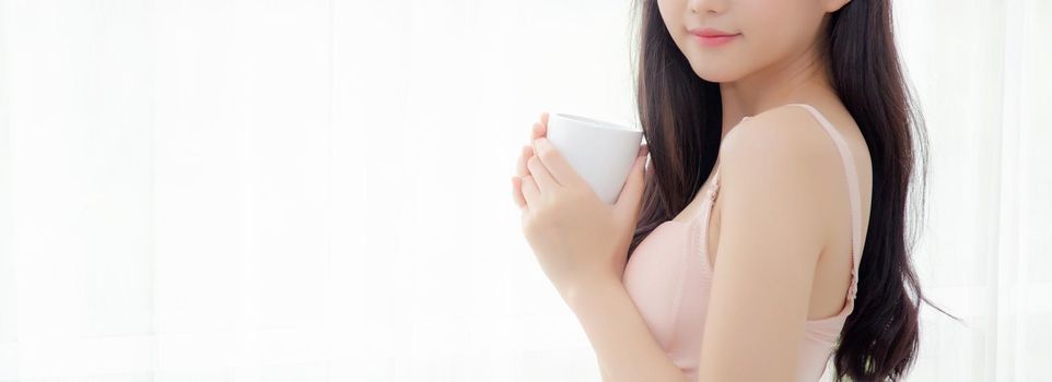 Closeup young asian sexy woman in underwear drinking coffee near windows, girl with seductive figure fit drinking beverage for relax and resting after wake up, lifestyle concept, banner website.