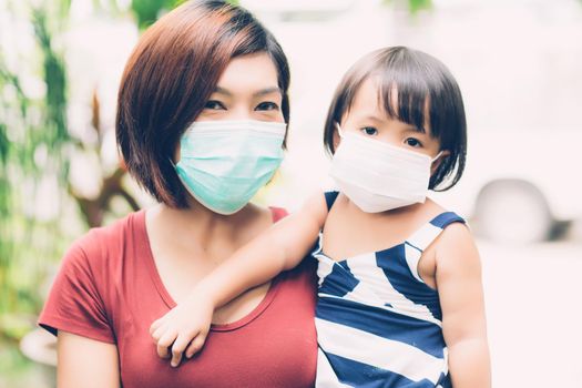 Mother take care daughter with face mask for protection disease flu or covid-19 outdoors, mom wearing on medical mask with child safety for protect outbreak of pandemic, medical concept.