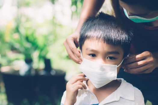 Mother take care son with face mask for protection disease flu or covid-19 outdoors, mom wearing on medical mask with child safety for protect outbreak of pandemic in public, medical concept.