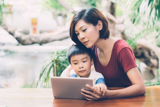 Son using digital tablet computer for study and learn to internet online with mother together, education from home, family recreation, mom teach boy with technology media, lifestyle concept.