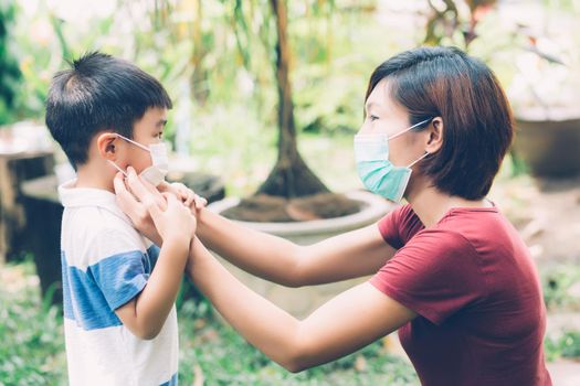 Mother take care son with face mask for protection disease flu or covid-19 outdoors, mom wearing on medical mask with child safety for protect outbreak of pandemic in public, medical concept.