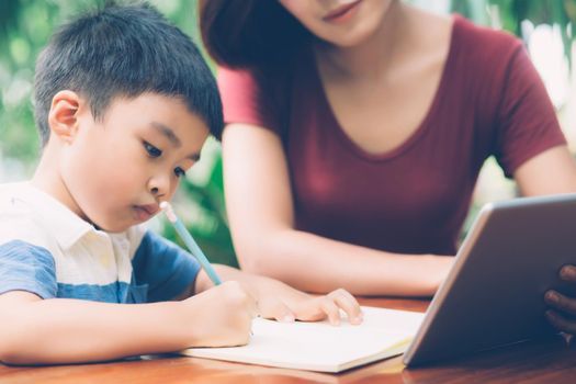 Son using digital tablet computer for study and learn to internet online with mother together, education from home, family recreation, mom teach boy and homework with technology, lifestyle concept.