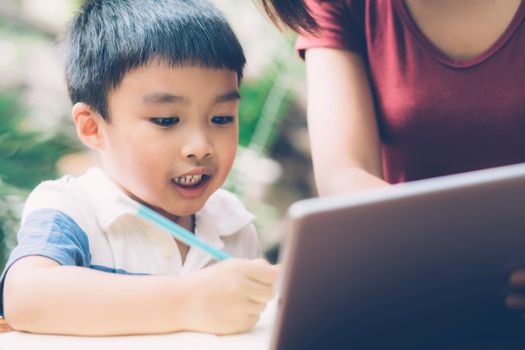 Son using digital tablet computer for study and learn to internet online with mother together, education from home, family recreation, mom teach boy and homework with technology, lifestyle concept.