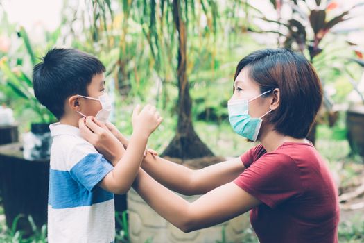 Mother take care son with face mask for protection disease flu or covid-19 outdoors, mom wearing on medical mask with child safety for protect outbreak of pandemic in public, medical concept.