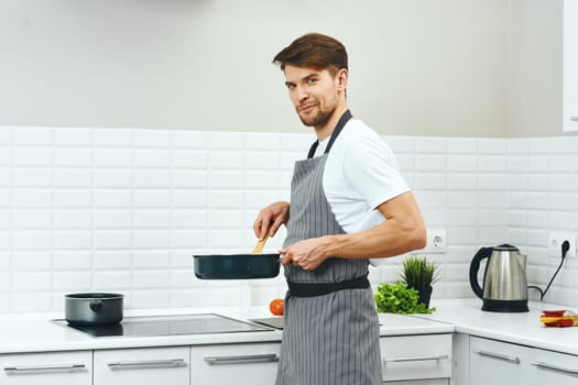 A male chef in gray aprons is holding a frying pan in his hands cooking food kitchen lifestyle