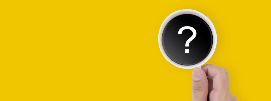 Hand holding cup of hot coffee with question mark isolated on yellow background, top view, q & a, faq or assistance for incentive, beverage, communication and idea concept, banner website.