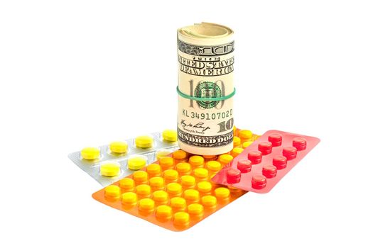 Rolled up banknotes next to medications. Treatment cost. Medical business. Pharmaceutical business. Objects isolated on white background.