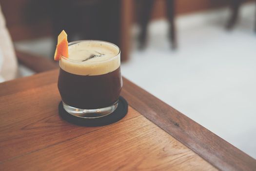 iced coffee mixing with orange syrup garnished with orange peel