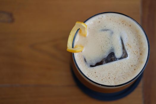 iced coffee mixing with orange syrup garnished with orange peel